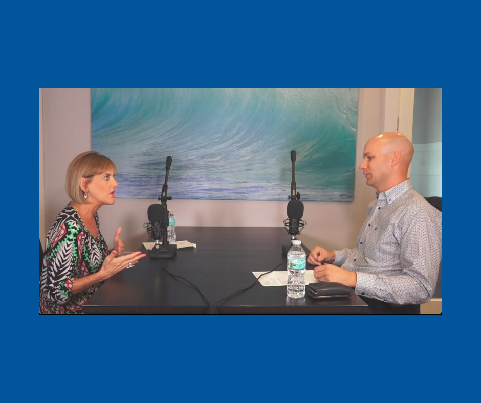 Podcast hosts engaged in a discussion at a table with microphones, featuring a wave painting in the background. The woman on the left expresses her thoughts animatedly, while the man on the right listens attentively. A water bottle and notes are visible on the table.