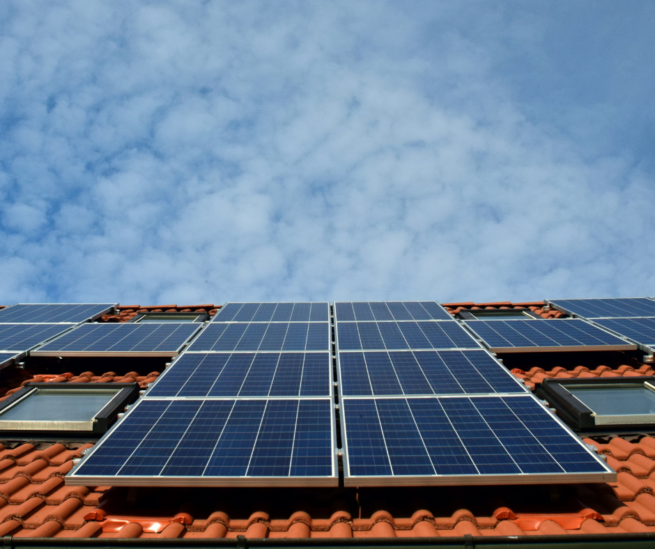 Solar panels installed on a tiled roof, capturing sunlight under a partly cloudy sky, promoting renewable energy use and sustainability.