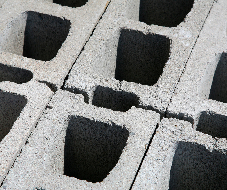 Close-up of concrete cinder blocks arranged in a grid pattern, showcasing the hollow centers and rough texture, commonly used in construction for walls and foundations.