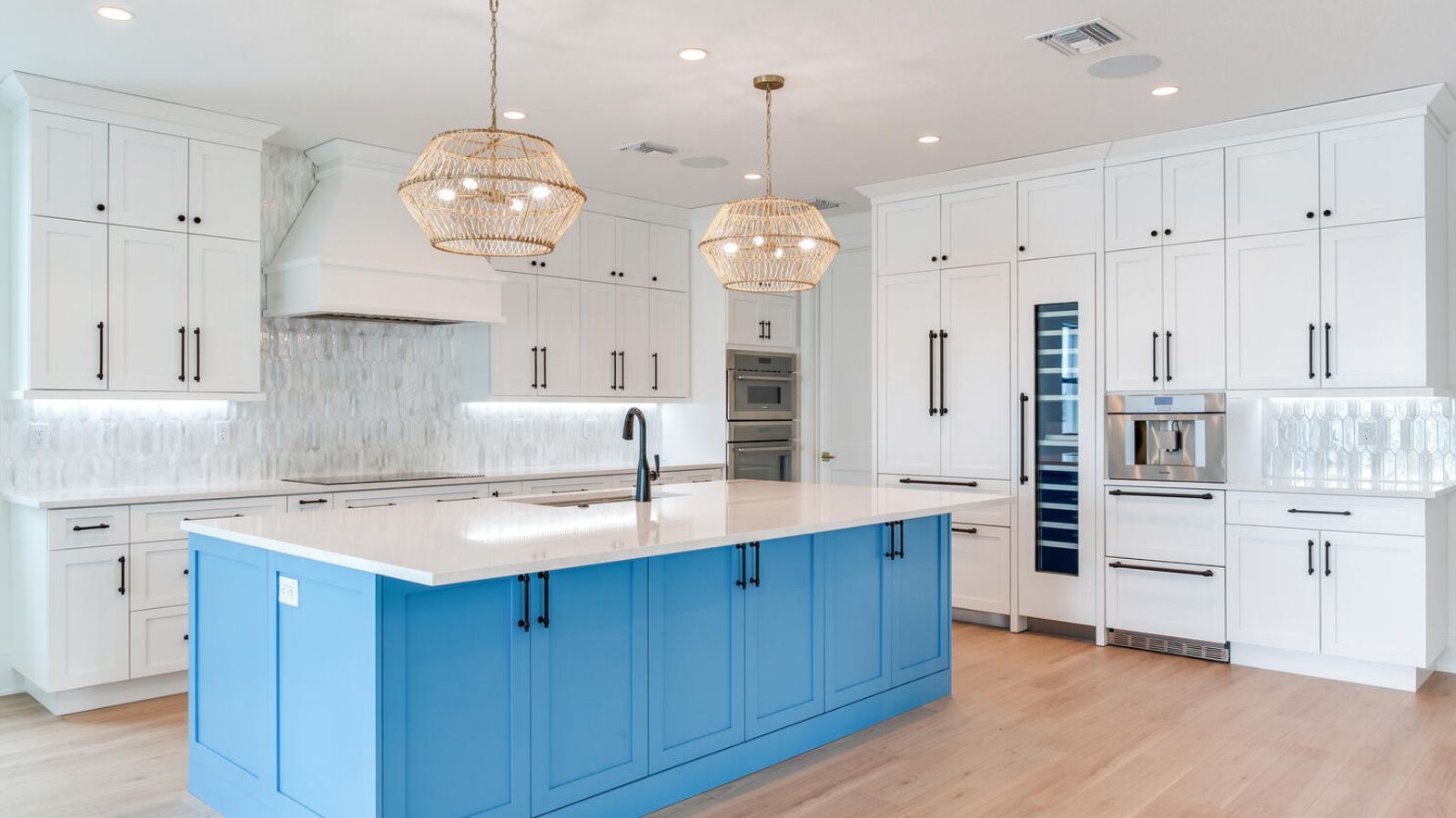 Modern kitchen design featuring a blue island, white cabinetry, and pendant lighting. The space includes stainless steel appliances, a stylish backsplash, and ample storage, creating a bright and inviting atmosphere. Perfect for cooking and entertaining.