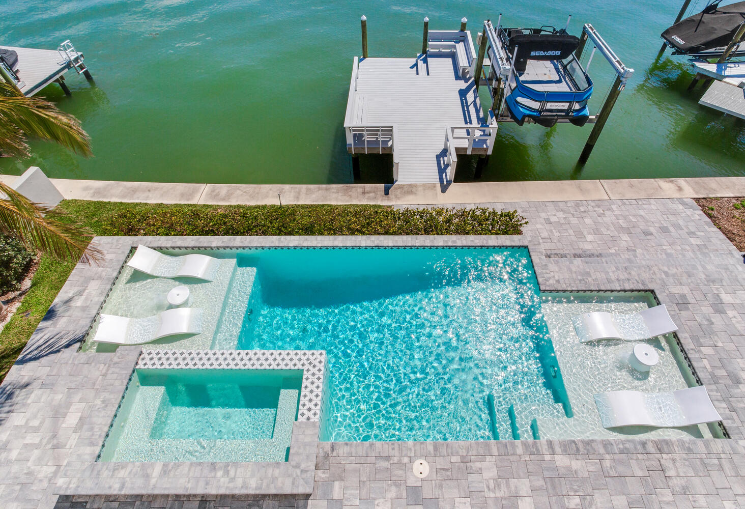 Aerial view of a pool and dock, showcasing the water and surrounding landscape.
