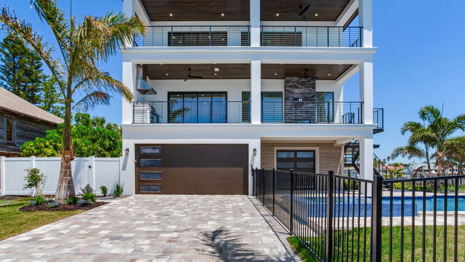 a home with a pool and palm trees in front of it