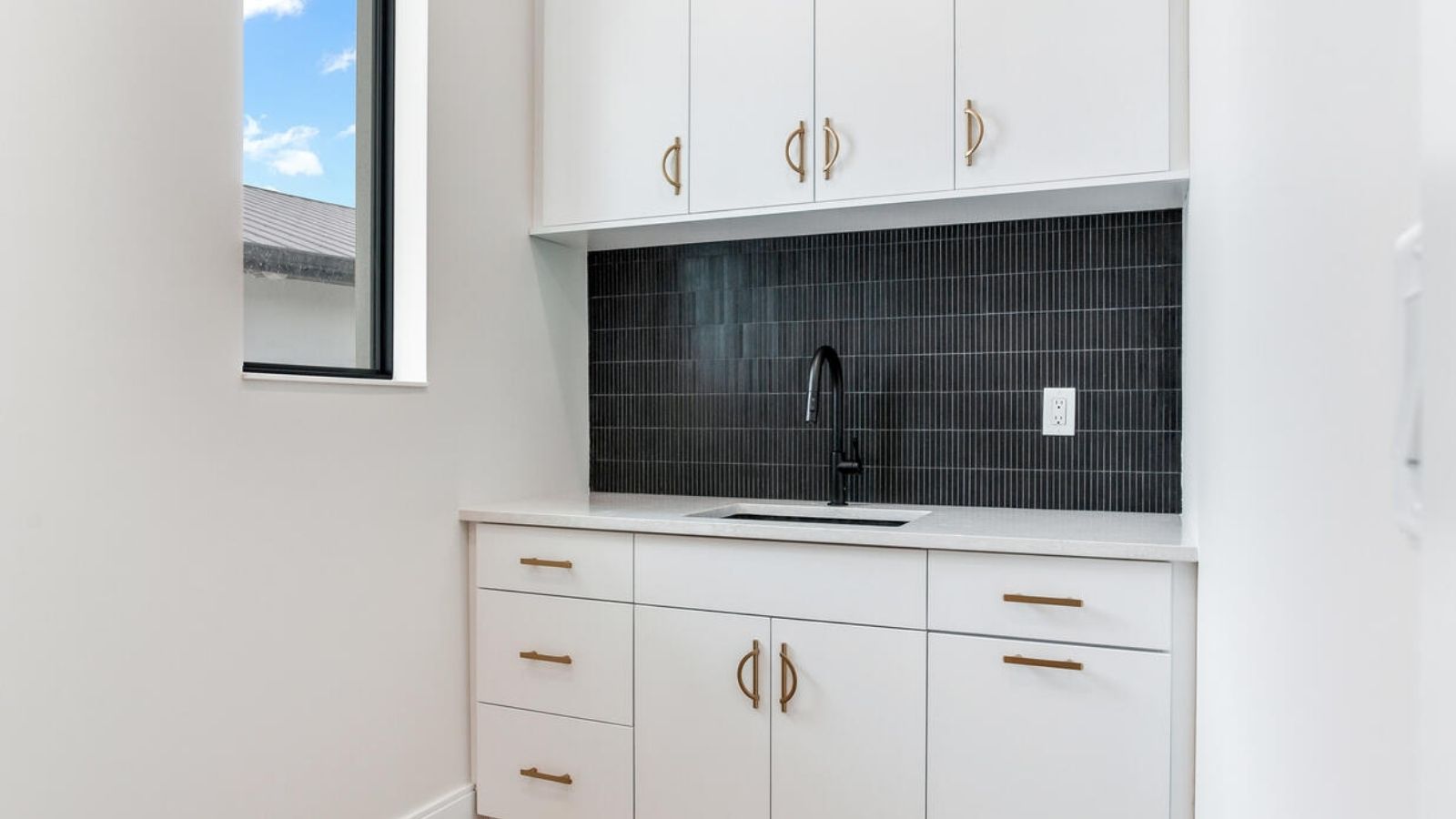 a kitchen with white cabinets and black tile backsplash