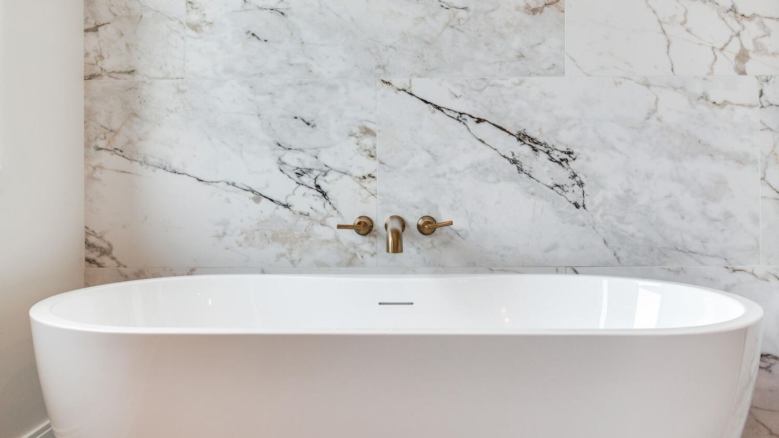 a bath tub sitting in front of a marble wall