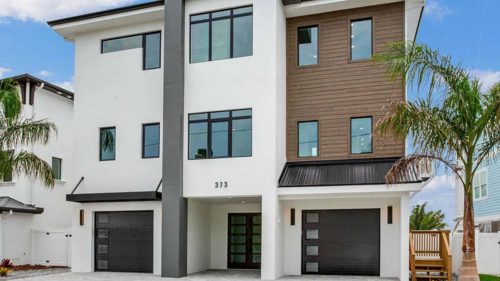 a modern home with two garages and palm trees