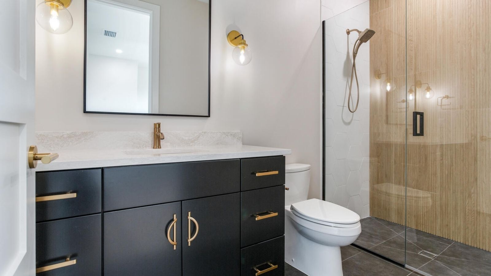 a modern bathroom with black cabinets and gold accents