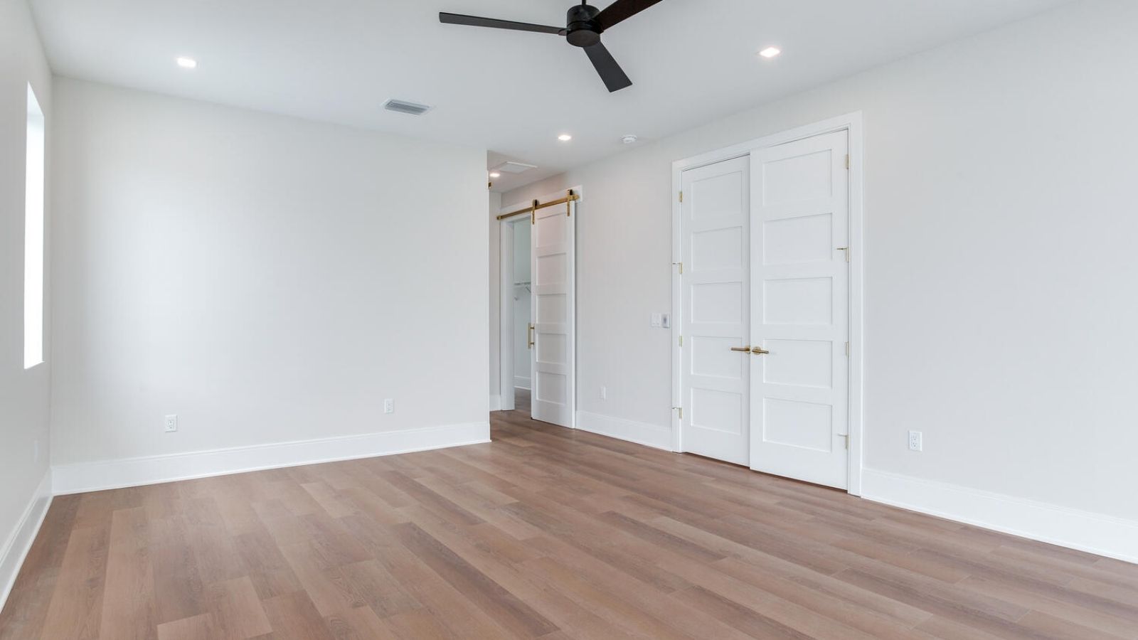 an empty room with hardwood floors and a ceiling fan