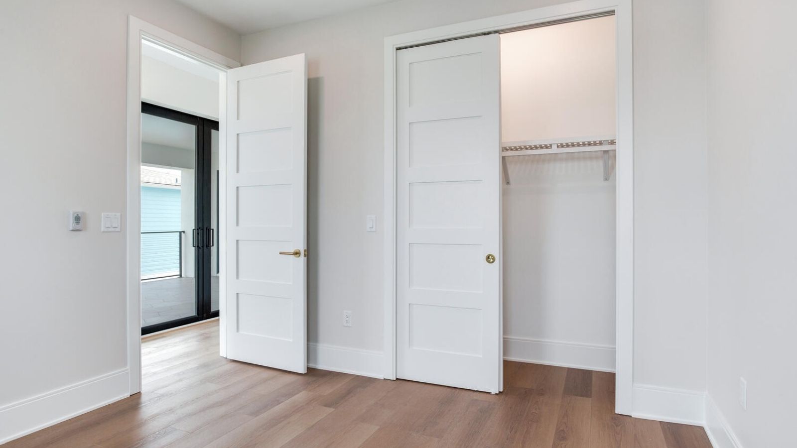 an empty room with white doors and hardwood floors