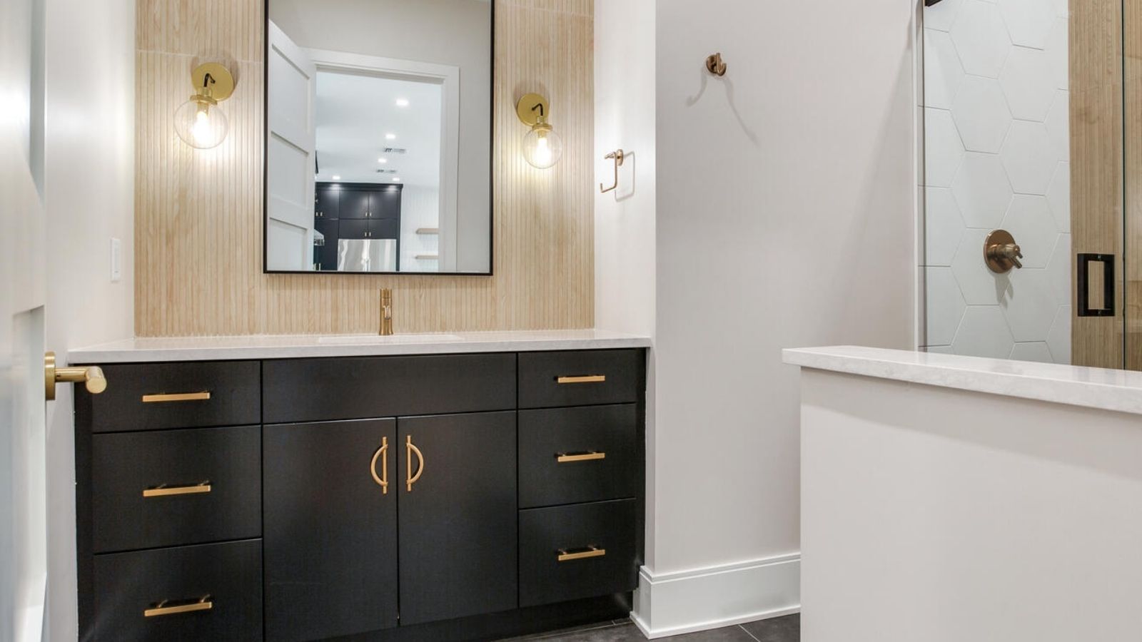 a bathroom with black cabinets and gold accents