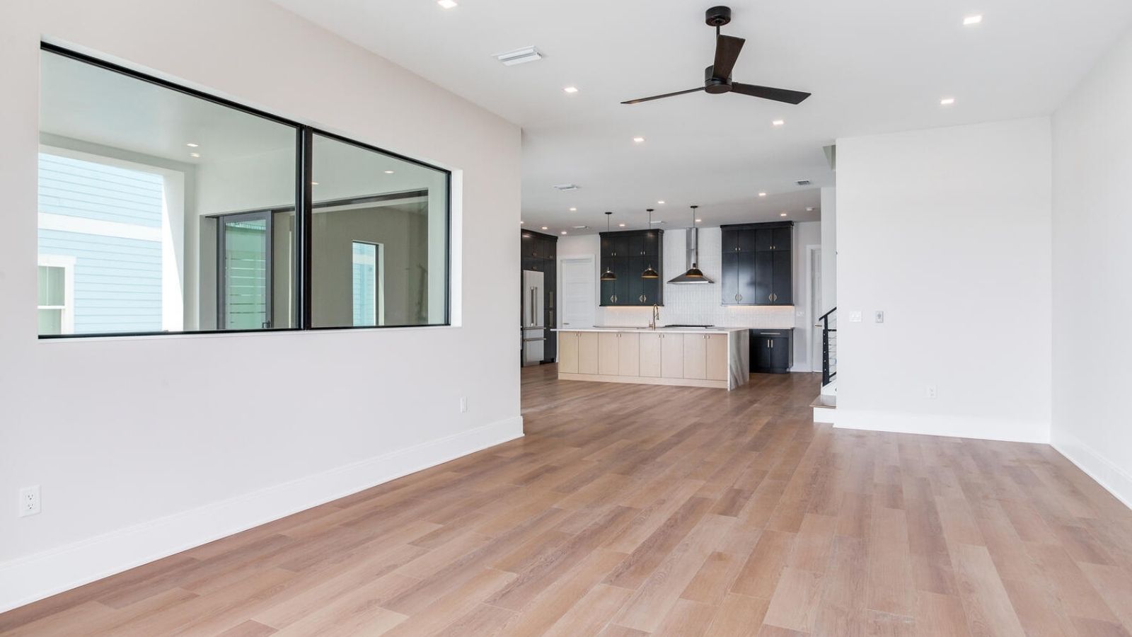 an empty living room with hardwood floors and a ceiling fan