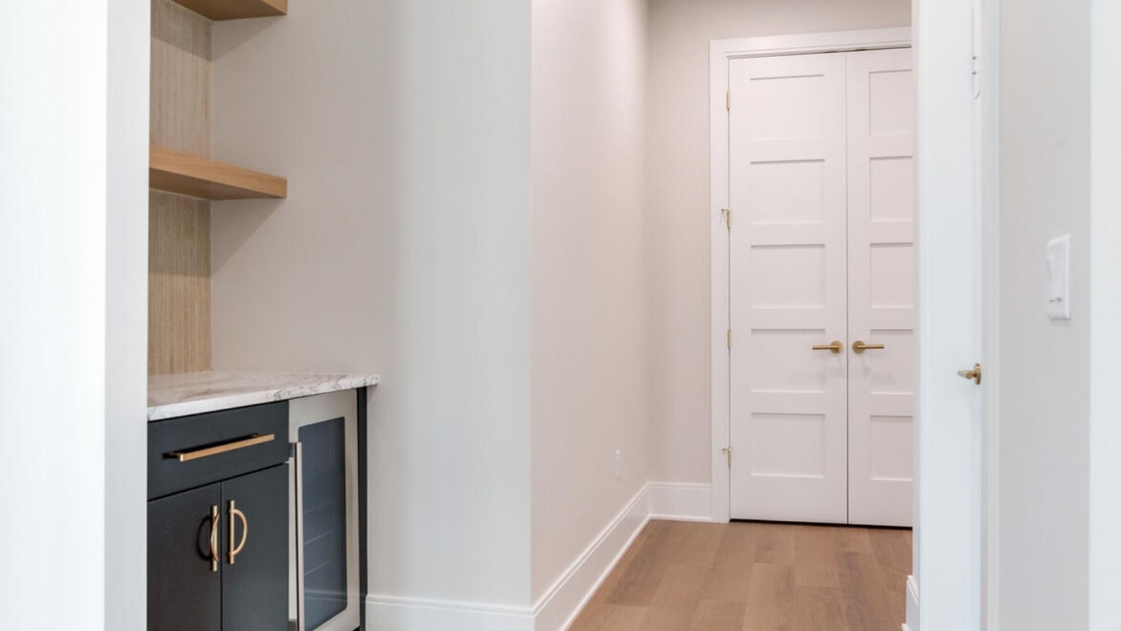a narrow hallway with white walls and wooden floors