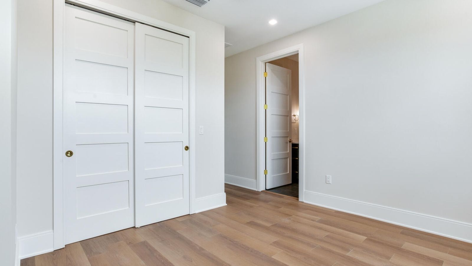 an empty room with hardwood floors and white closets