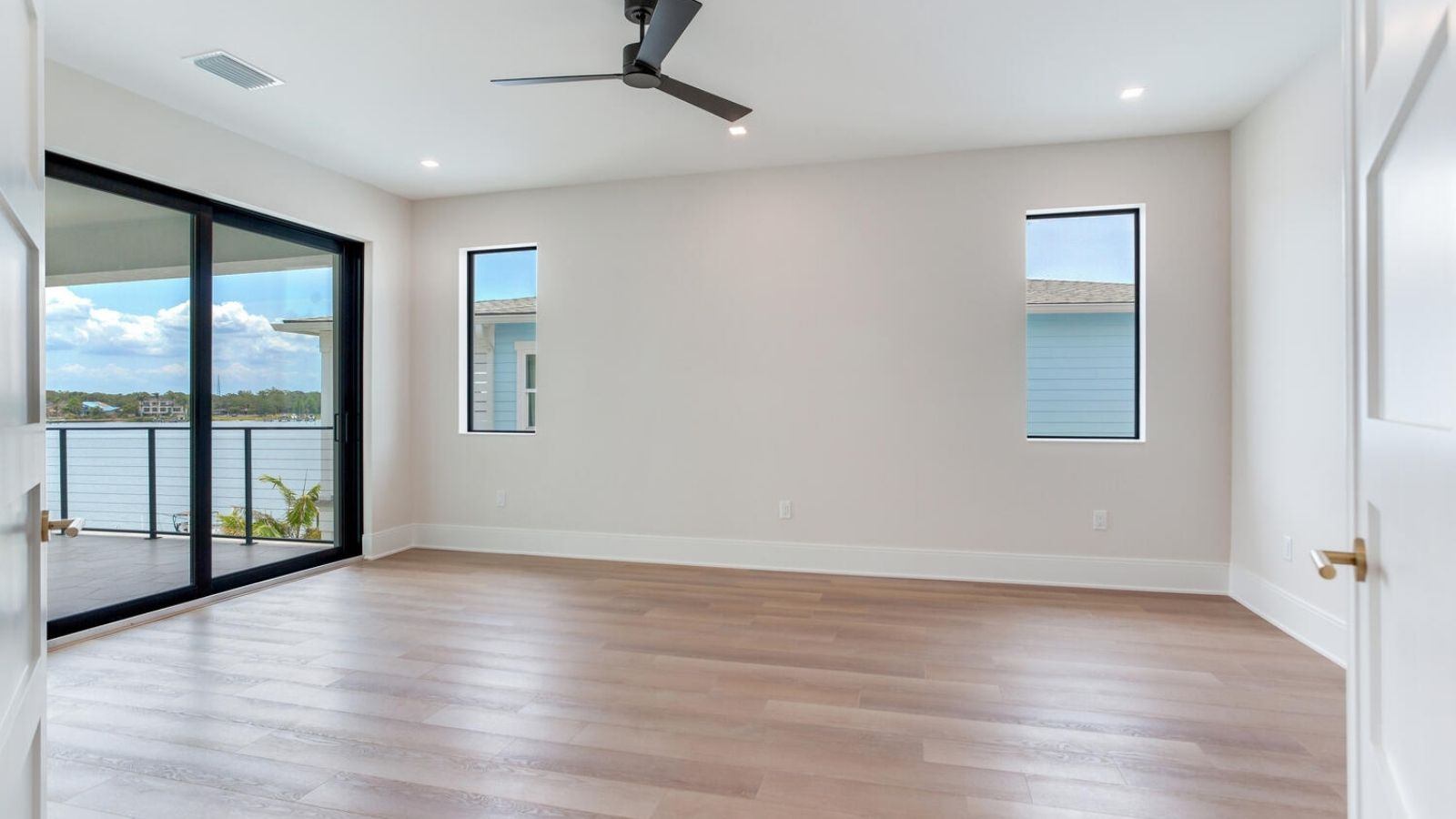 an empty room with hardwood floors and sliding glass doors