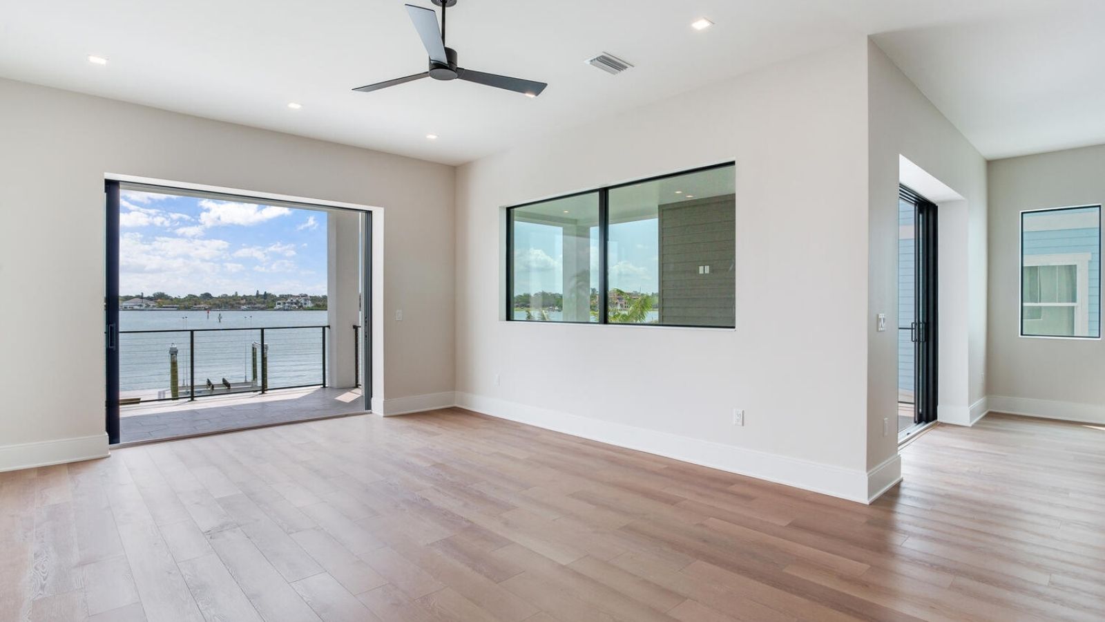 an empty living room with hardwood floors and a view of the water