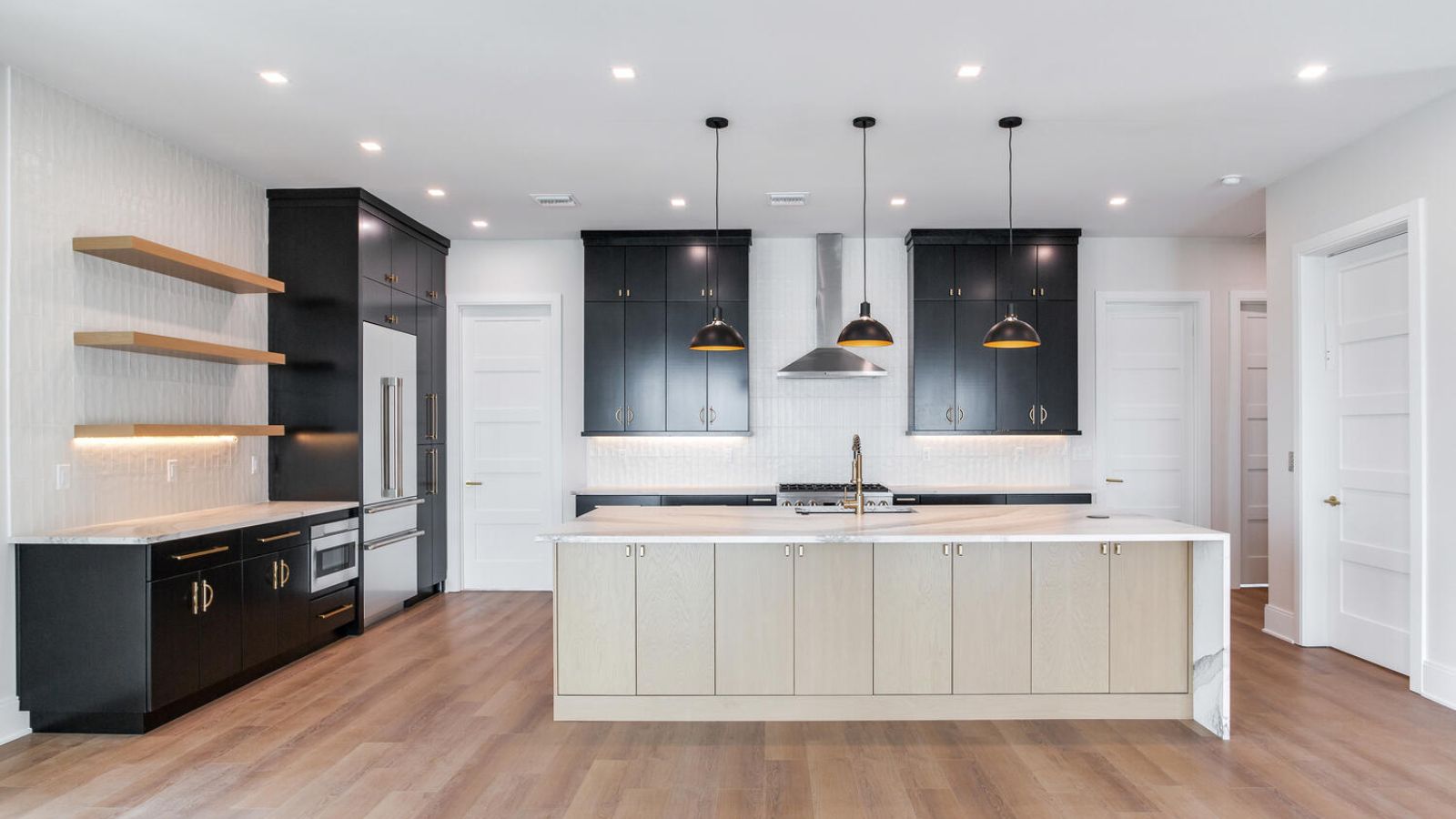 a modern kitchen with wood floors and black cabinets