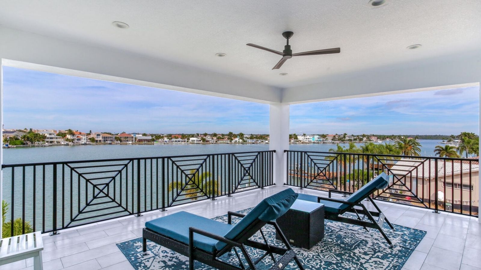 a balcony with wicker chairs and a view of the water
