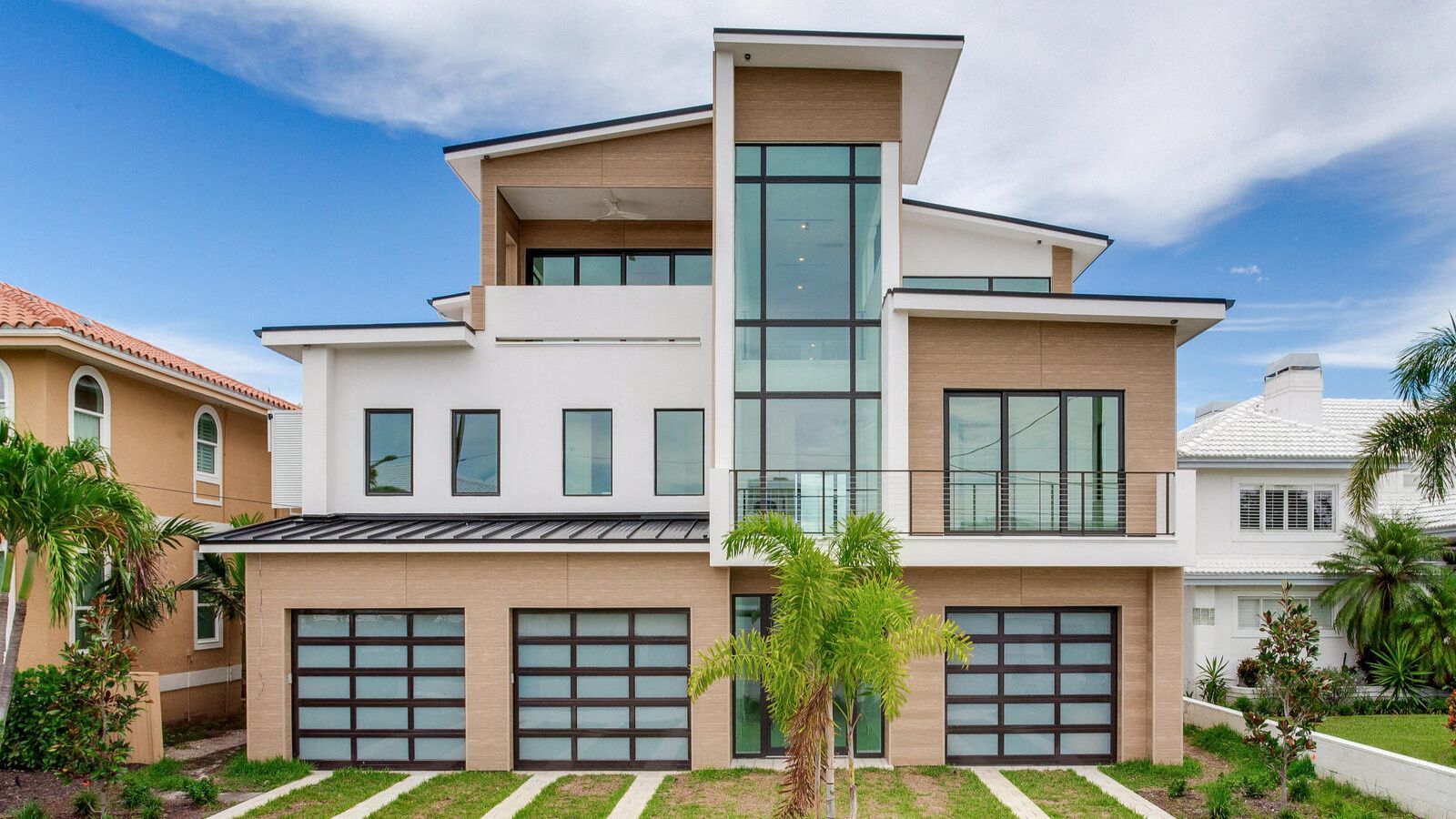 Front view of modern coastal home with large windows and balconies