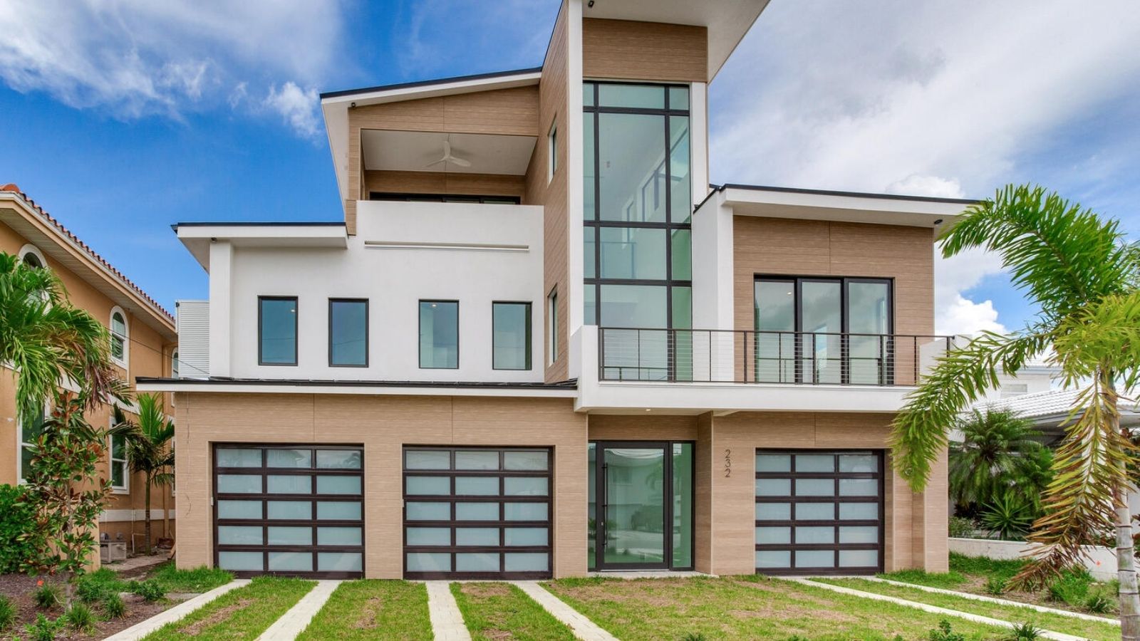 Rear exterior view showcasing modern coastal architecture with expansive windows and multi-car garage.