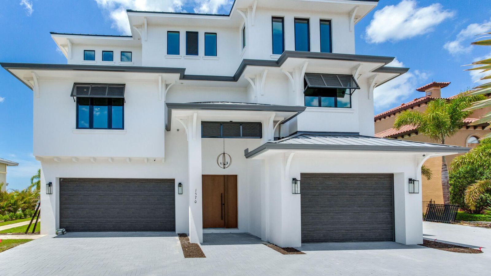 Contemporary home exterior with clean lines, dual garages, modern entry door, and bold coastal-inspired architecture
