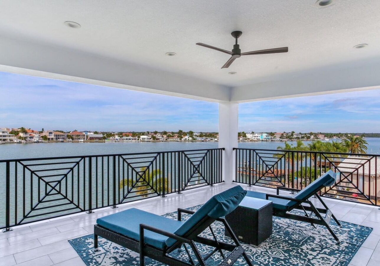 a balcony with wicker chairs and a view of the water